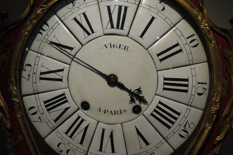 Detailaufnahme eines antiken Wanduhrs mit römischen Ziffern und dem Namen "VIGER A:PARIS" auf dem Zifferblatt.